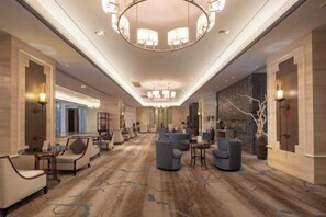A spacious hotel lobby with a central seating area, a chandelier, and a carpeted floor. - Jing Jiang Hotel (Lianjiang)