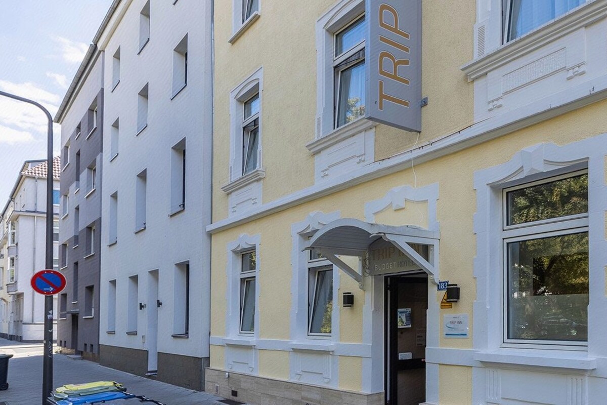 A building with a sign indicating a budget hotel, a no parking sign, and a row of parked bicycles.