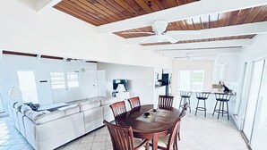A spacious living area with a dining table, chairs, a sofa, and a kitchen in the background. - Blue Bird Villa, Open & Breezy Island Home...minutes from the beach! (Providenciales)