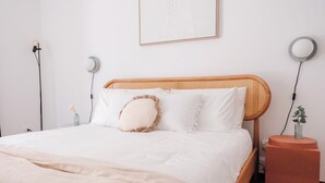 A neatly made bed with a white comforter and a beige throw blanket.