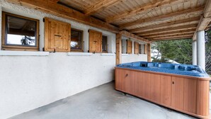 A covered outdoor area with a hot tub, wooden windows, and a concrete floor. - Spacious chalet in La Rosière with hammam and jacuzzi for 15 people (Montvalezan-La Rosière)