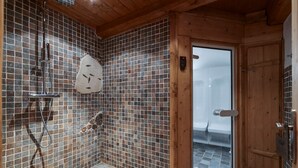 A bathroom with mosaic tile walls, a shower with a handheld showerhead, and a wooden door leading to a shower area. - Spacious chalet in La Rosière with hammam and jacuzzi for 15 people (Montvalezan-La Rosière)