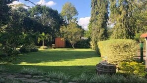 Un jardín con césped, una estructura de ladrillo y un cobertizo de madera.