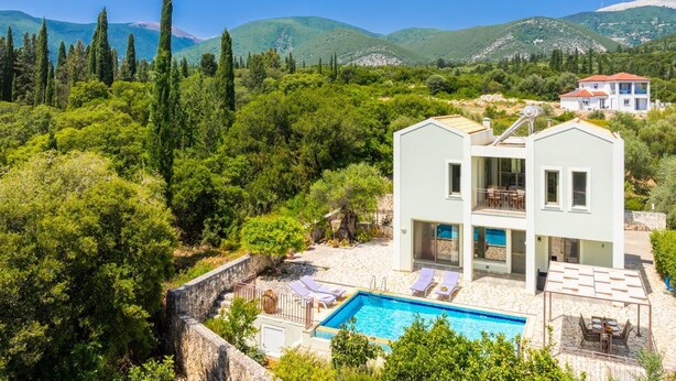 Une maison moderne à deux étages avec une piscine, entourée d’une végétation luxuriante et de montagnes.