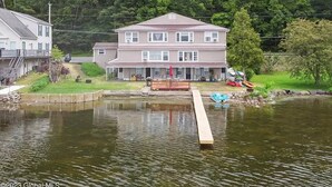 A two-story house with a dock extending into a lake, surrounded by greenery. - Saratoga Lakeside Retreat #3 (Saratoga Springs)