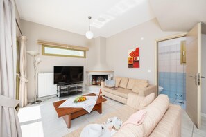 Ein modernes Wohnzimmer mit Fernseher, Sofa, Couchtisch und Kamin.