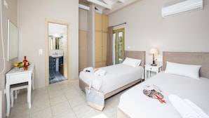 Habitación de hotel con dos camas, baño y una pequeña zona de estar.