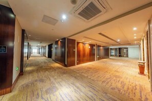 A hotel corridor with carpeted flooring, wooden doors, and a trash bin. - Luling Hotel (Ji'an County)