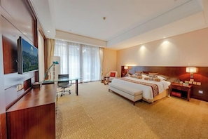 A hotel room with a large bed, a desk with a chair, a television, and a window with curtains. - Luling Hotel (Ji'an County)