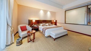 Una camera d'albergo con un letto, una sedia, un tavolino, un comodino e un'ampia finestra.