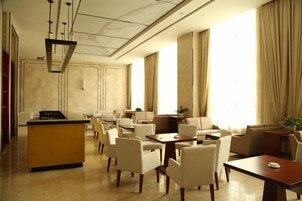 Un vestíbulo de hotel con una isla central, zona de estar y amplios ventanales.