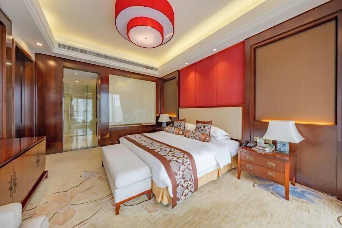 Quarto de hotel com uma cama grande, uma mesa de cabeceira, uma escrivaninha e um guarda-roupa.