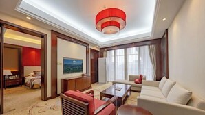 Una camera d'albergo con divano, poltrona, tavolino e un quadro appeso al muro.