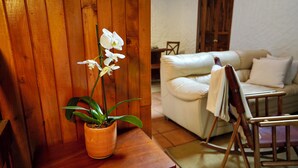 A potted orchid on a wooden table, a white sofa, and a wooden rocking chair in a room with wooden walls. - La Auxiliadora - Classic Mountain Chalet (Montecito)