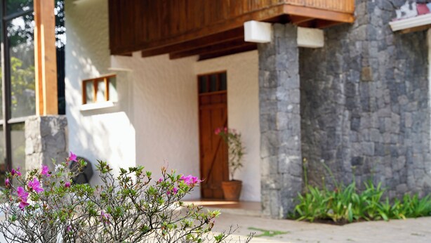 A building with a stone facade, a wooden door, and a small window. - La Auxiliadora - Classic Mountain Chalet (Montecito)
