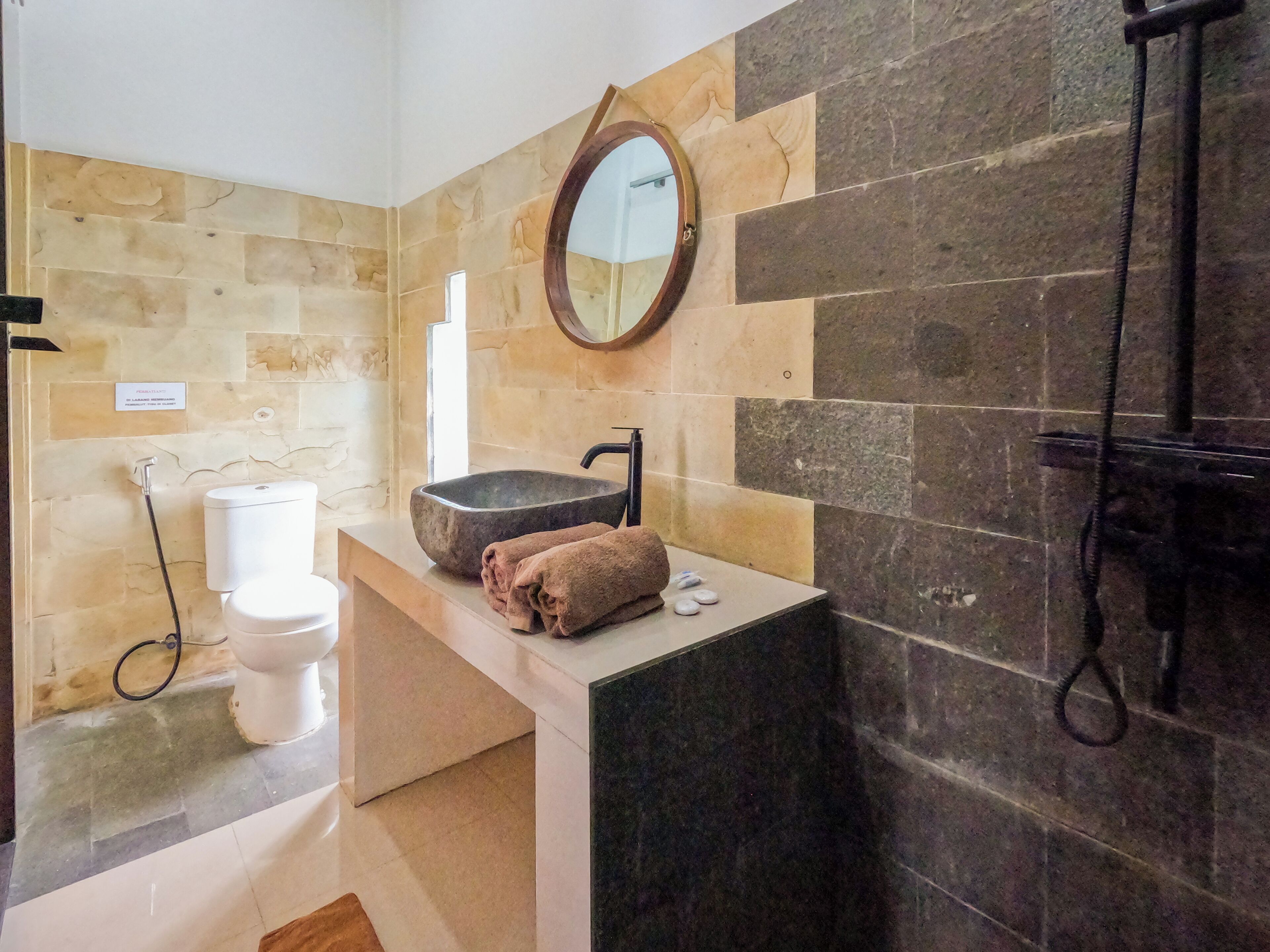 Une salle de bain avec un lavabo en pierre, un miroir, une serviette et une douche.