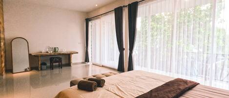 A spacious bedroom with a large bed, a desk, and a mirror.