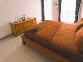 Un dormitorio con cama y cómoda de madera, y una ventana con cortinas.