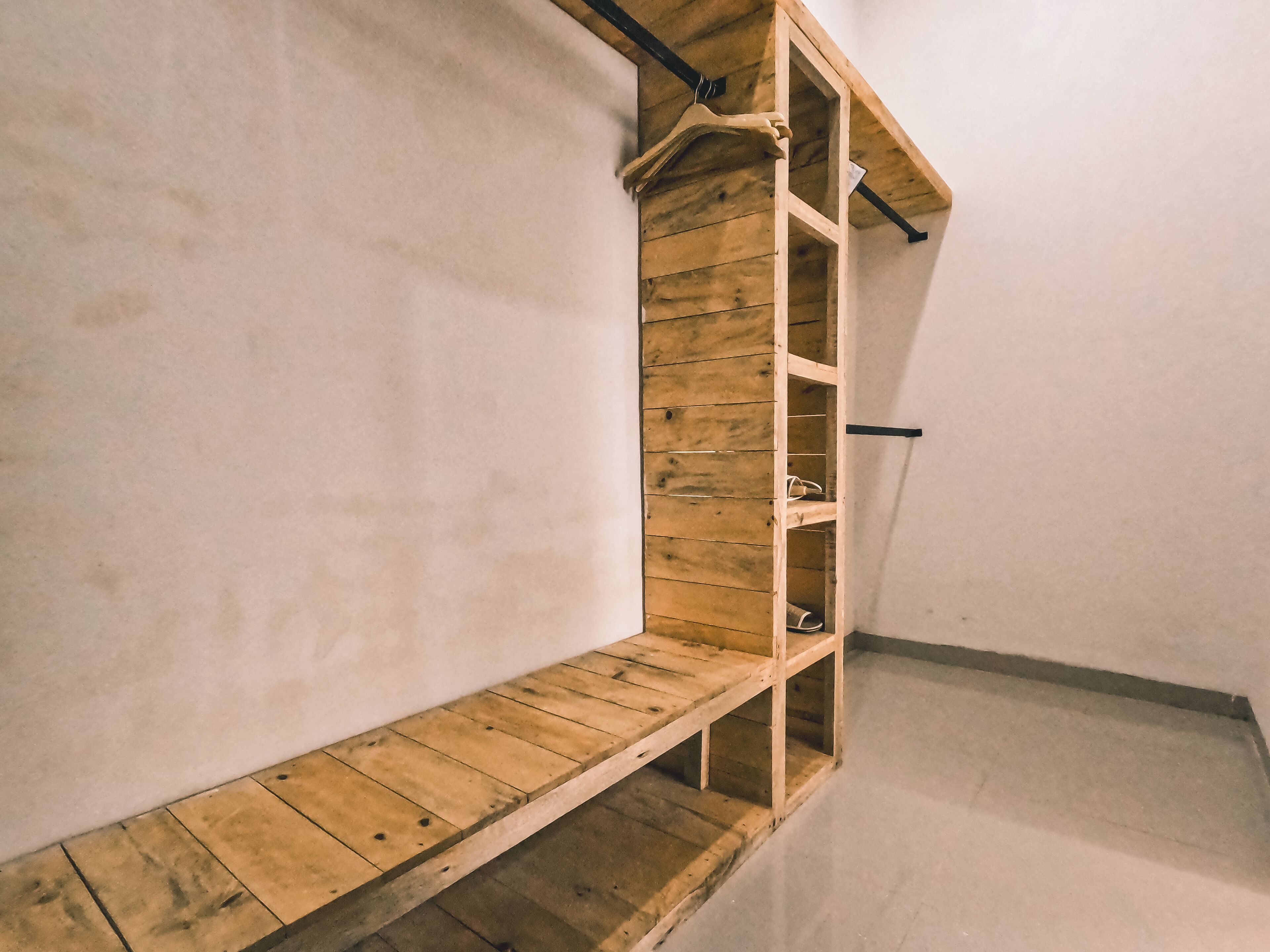 A corner of a room with a wooden bench and a built-in shelving unit against a white wall.