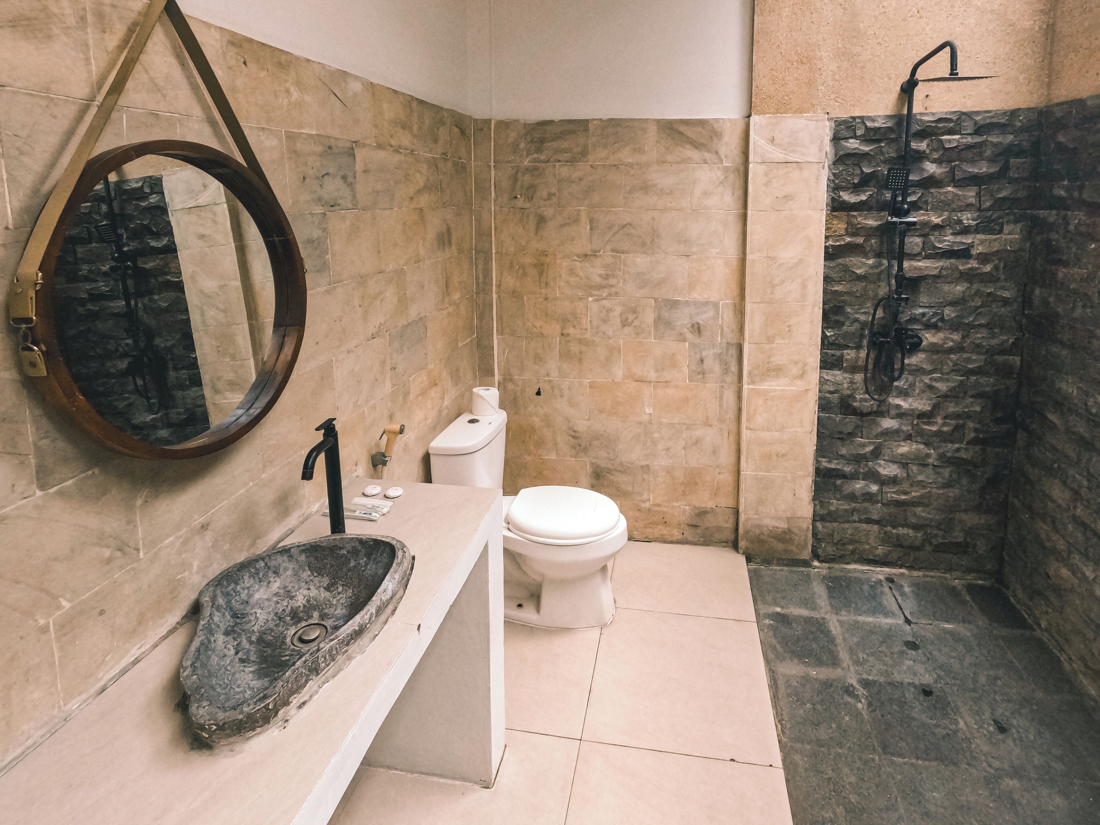 Ein Badezimmer mit einem Steinklopfbac, einer Toilette und einer Dusche mit einer Steinwand.