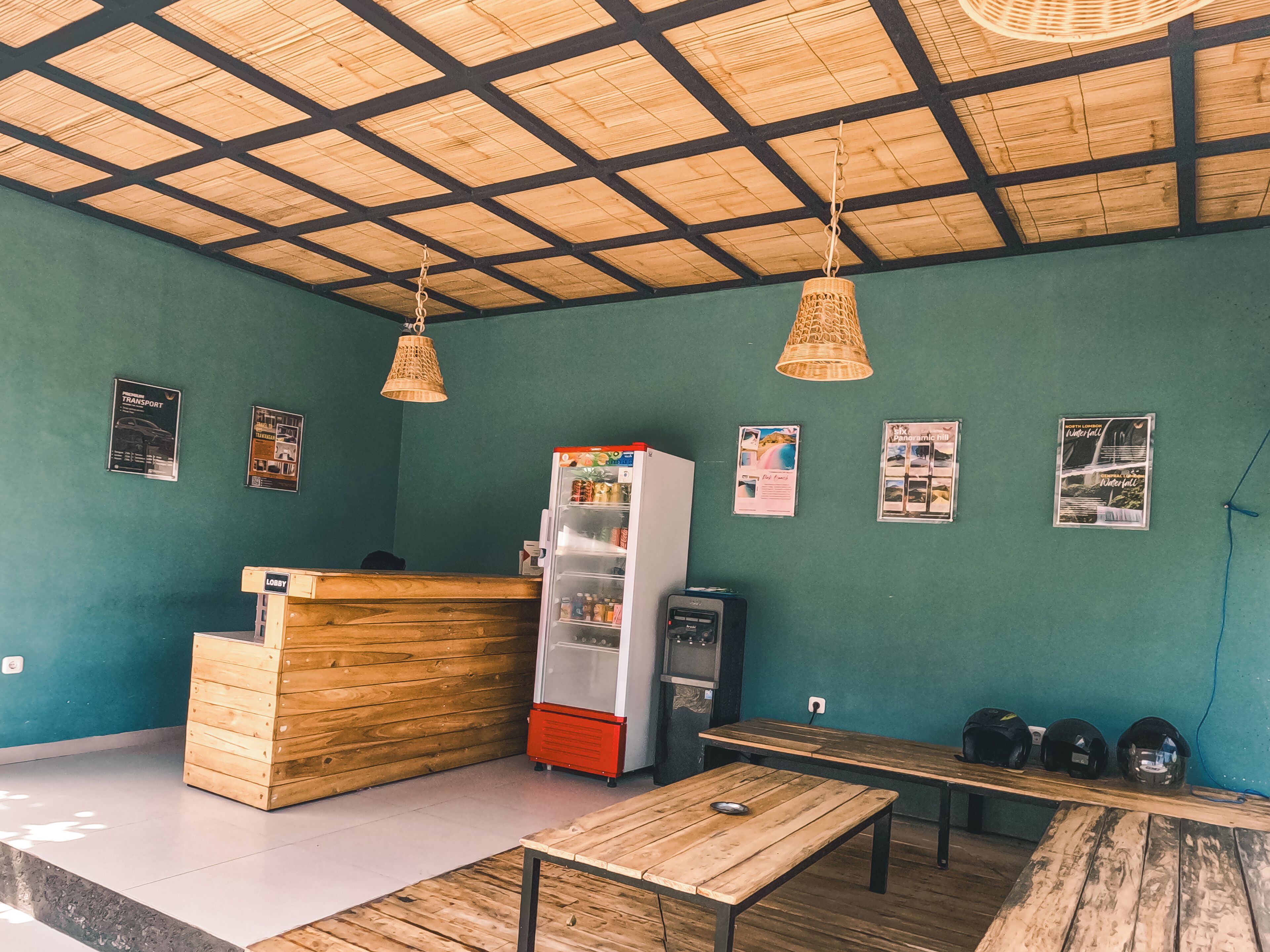 A restaurant with a wooden counter, a refrigerator, and a seating area with benches.