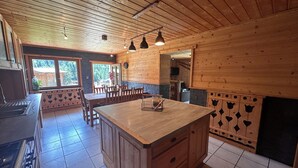 Cozinha de cabana rústica, com ilha central, armários de madeira e piso de azulejos.