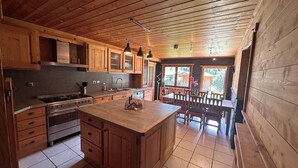 Uma cozinha com armários de madeira, uma ilha central e uma área de jantar com cadeiras e mesa.