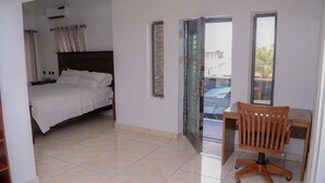 A bedroom with a bed, a desk with a chair, and a bathroom with an air conditioner. - Bamgbose Apartments in Surulere, Lagos Nigeria (Lagos)