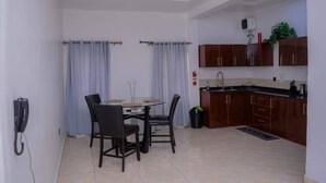 A modern kitchen with dark wooden cabinets, a built-in oven, and a sink. There is a dining area with a table and chairs, and a telephone on the wall. - Bamgbose Apartments in Surulere, Lagos Nigeria (Lagos)