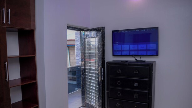 Ein Zimmer mit an der Wand montiertem Fernseher, einem schwarzen Aktenschrank und einem Holzschrank.
