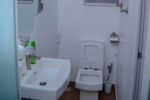 A small, compact bathroom with a white sink, toilet, and a small mirror. - Bamgbose Apartments - Sleeps 2 - Parking - Wifi (Lagos)