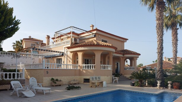 A large house with a swimming pool, outdoor furniture, and palm trees. - Costa Blanca Luxury villa with private pool on exclusive development (San Miguel de Salinas)