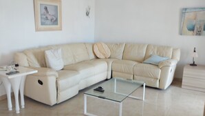 A modern living room with a beige sectional sofa, a glass coffee table, and a white side table. - Costa Blanca Luxury villa with private pool on exclusive development (San Miguel de Salinas)