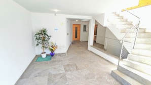 A spacious hallway with a marble floor, a potted plant, a small table, and a staircase with a metal railing. - Vidora Apartments - Dolomites relaxing Skyline Retreat (Ritten)