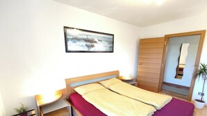 A bedroom with a bed, a nightstand, a small table with a lamp, a potted plant, and a wooden wardrobe. - Vidora Apartments - Dolomites relaxing Skyline Retreat (Ritten)