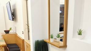 Una habitación moderna y minimalista con un banco de madera, una pequeña mesa y un espejo en la pared.