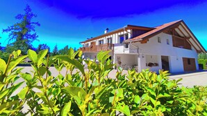 Una casa de dos pisos con balcón, rodeada de vegetación.