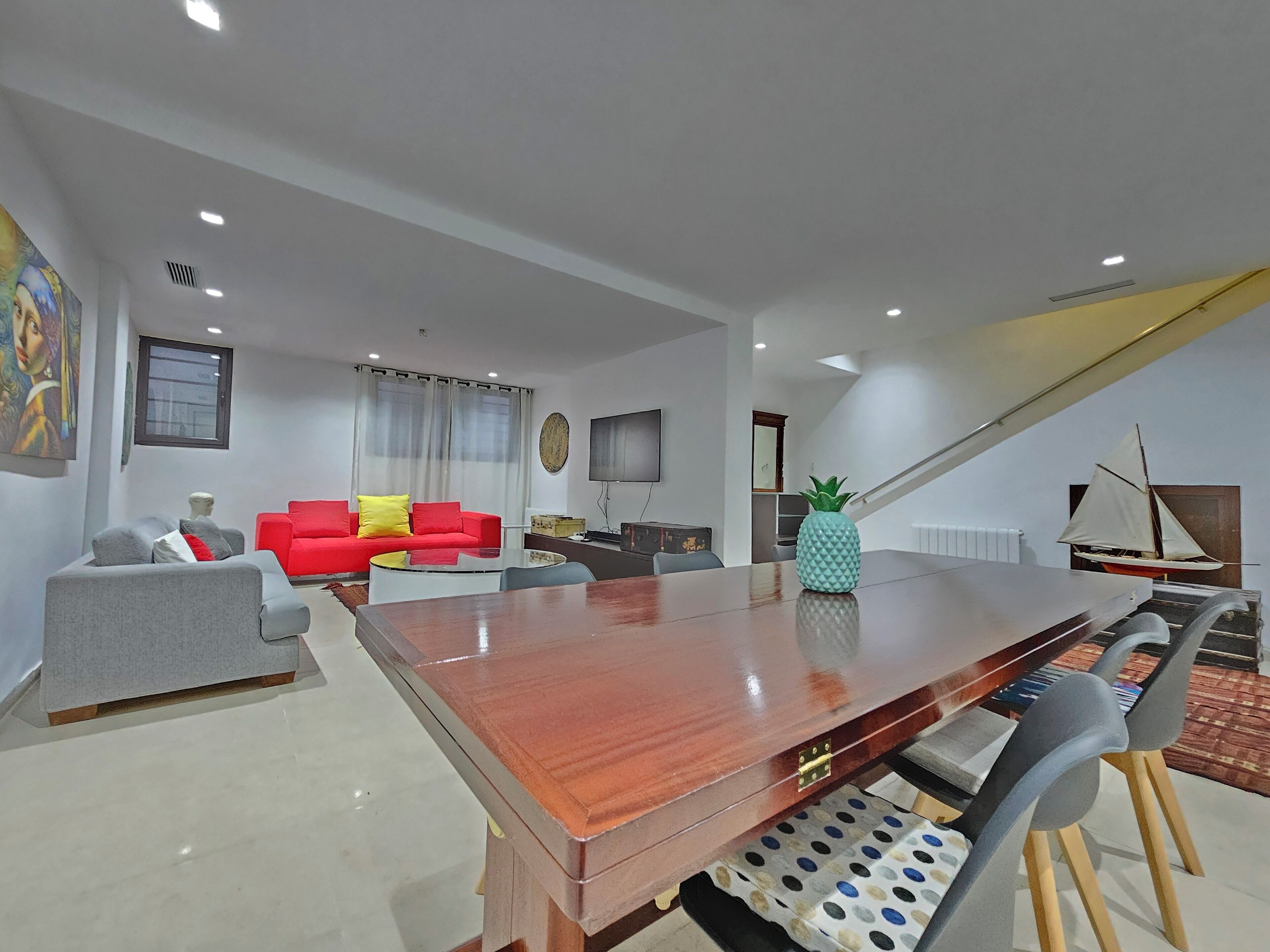A modern living room with a wooden coffee table, a red sofa, a grey sofa, and a pineapple decoration.