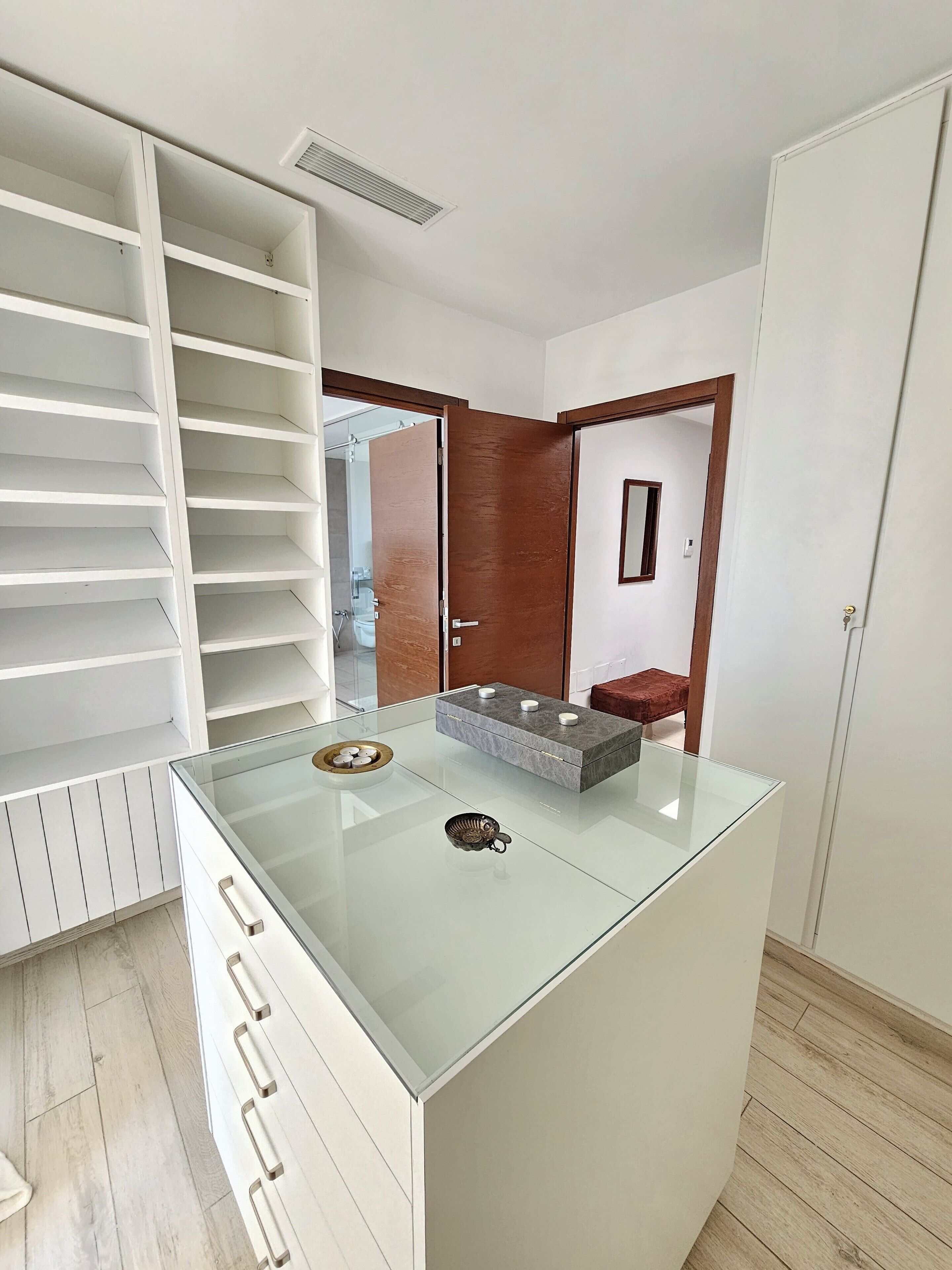 Une salle de bain moderne dotée d’une douche à parois de verre, d’un meuble-lavabo en bois et d’un meuble de rangement blanc.