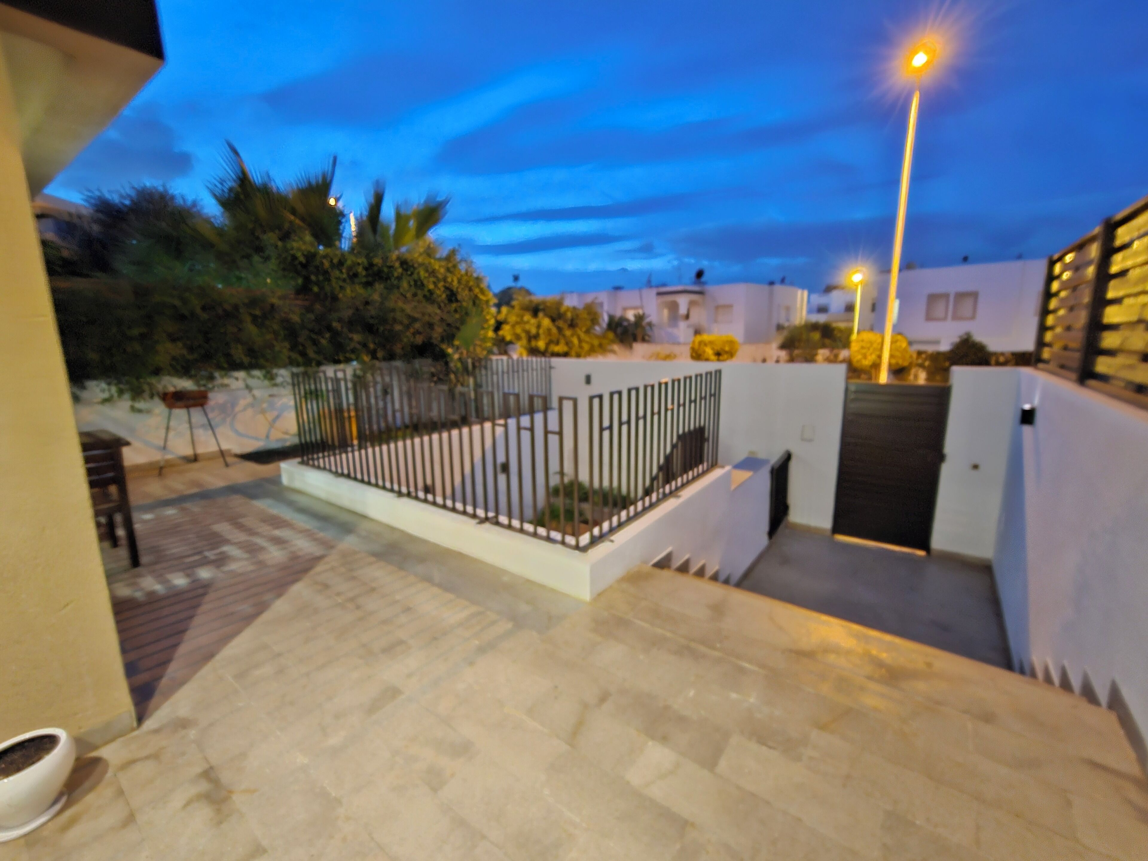 A courtyard with a paved floor, a metal fence, and a gate.