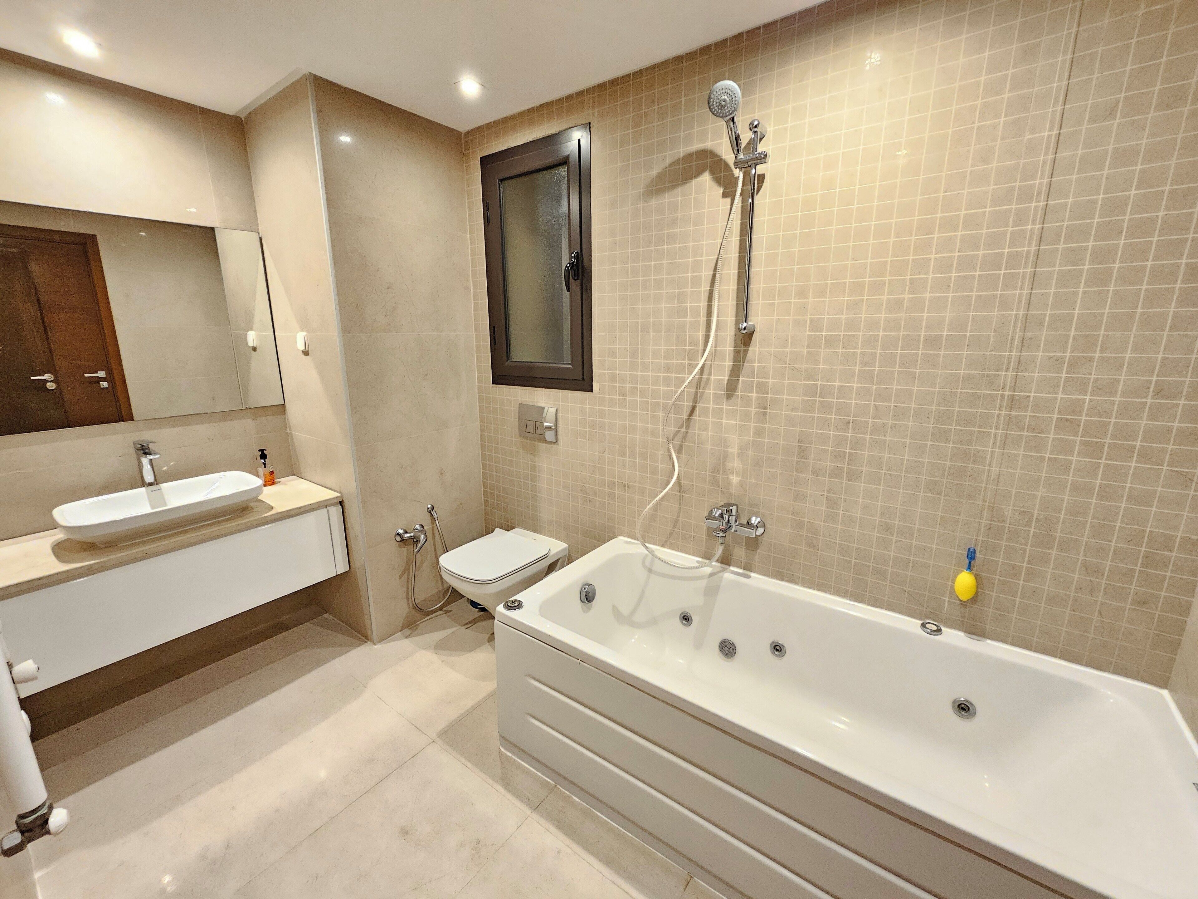A modern bathroom with a large bathtub, a separate toilet, and a vanity with a sink.