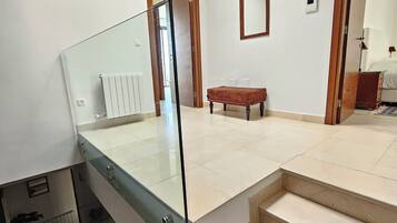 Un intérieur moderne avec un escalier en verre, un banc en bois et une verrière.