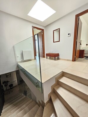 Een modern interieur met een glazen trap, een houten bank en een dakraam.