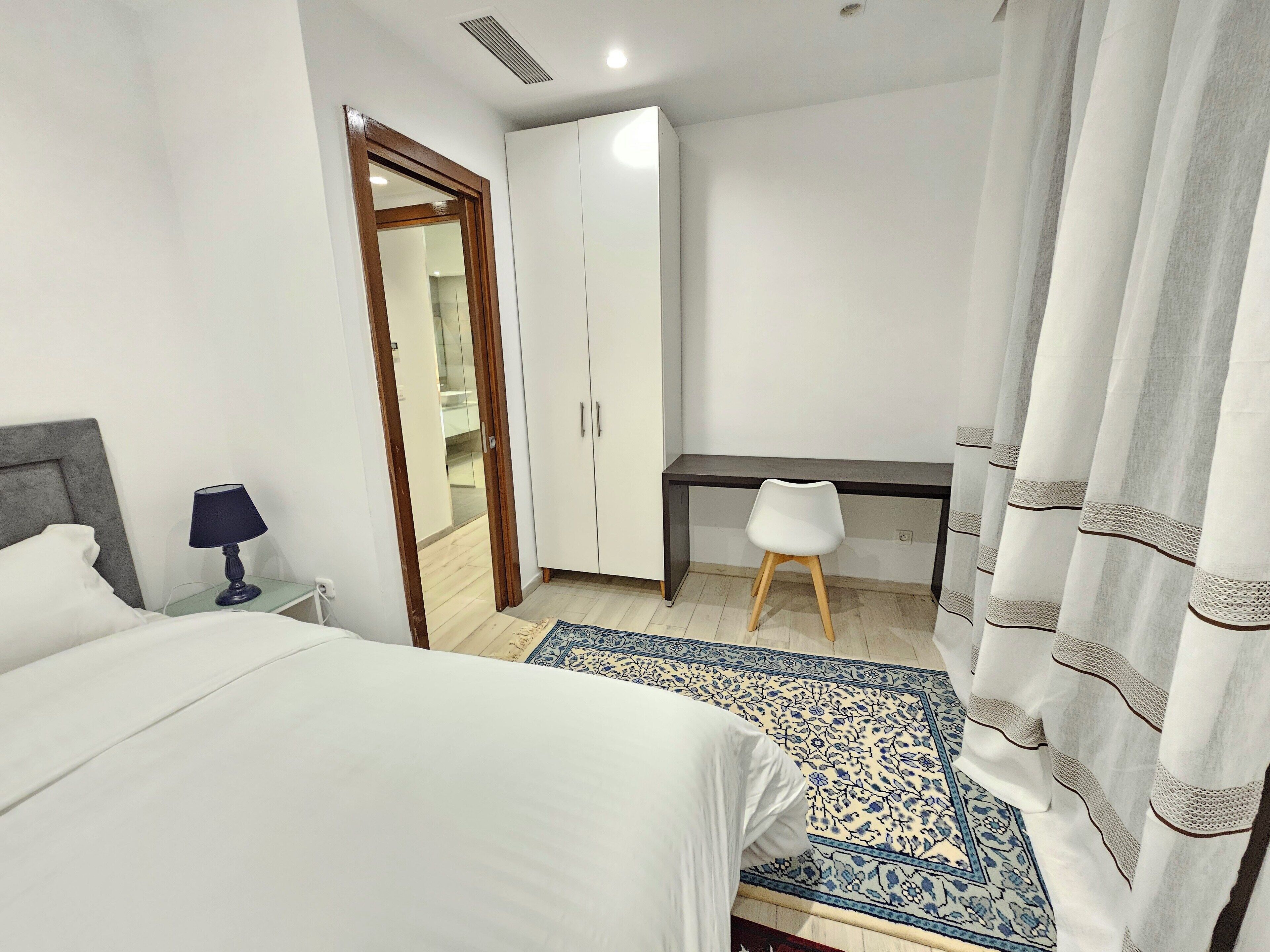 A bedroom with a bed, a desk, a chair, and a wardrobe.