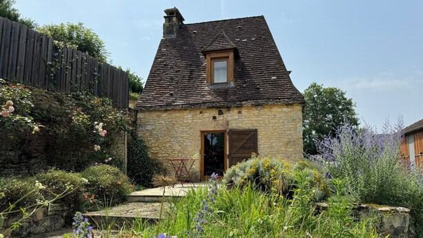 A stone house with a sloped roof, a wooden door, and a small window.