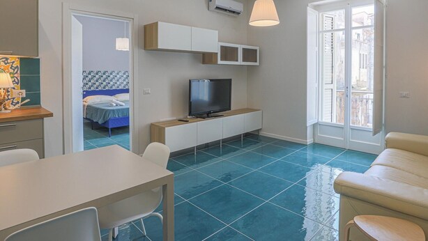Una sala de estar moderna con televisor, sofá y comedor.