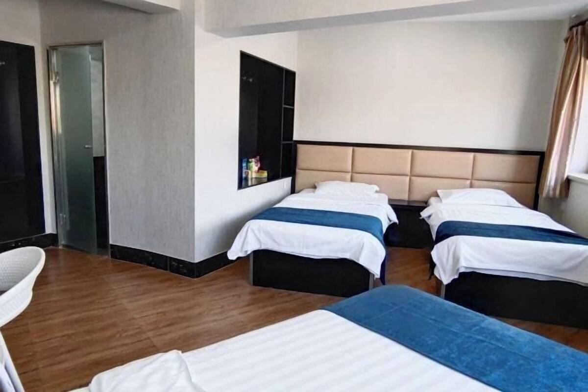 A hotel room with two beds, a seating area, a wardrobe, and a window.