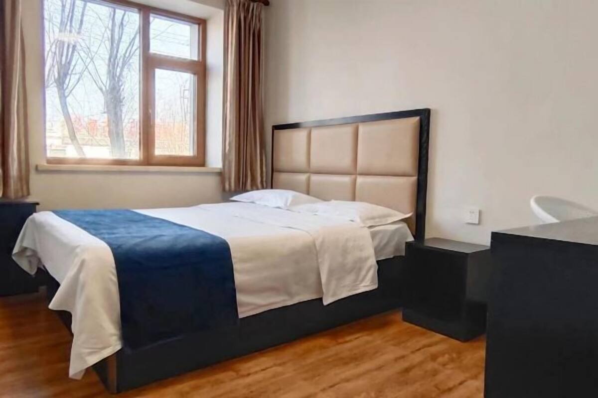 A bedroom with a bed, a window, and a desk.