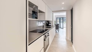 Una cucina moderna con elettrodomestici integrati, un'area pranzo con tavolo e sedie e vista all'esterno tramite una porta in vetro.