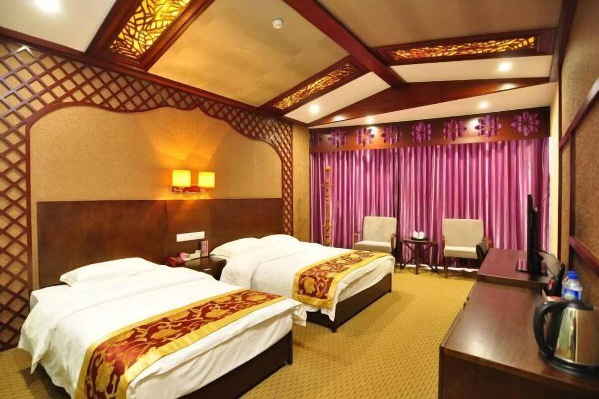 Een hotelkamer met twee bedden, een bureau, een stoel en een televisie.